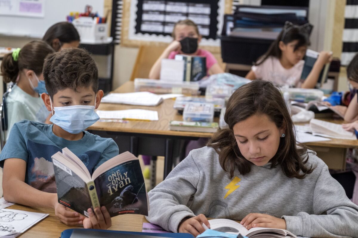 Two students, one in a mask, read in class at Pomelo Community Charter School.