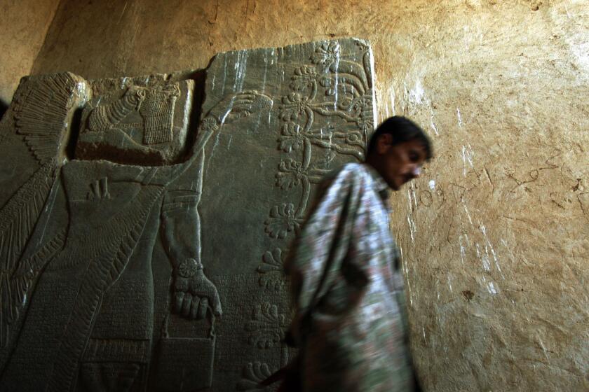 A guard at the ancient city of Nimrud, Iraq, walks in 2003 past an alabaster bas relief dating to between 800 and 900 BC.