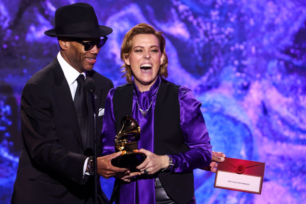 A very happy lady in purple gets an award from a man in sunglasses