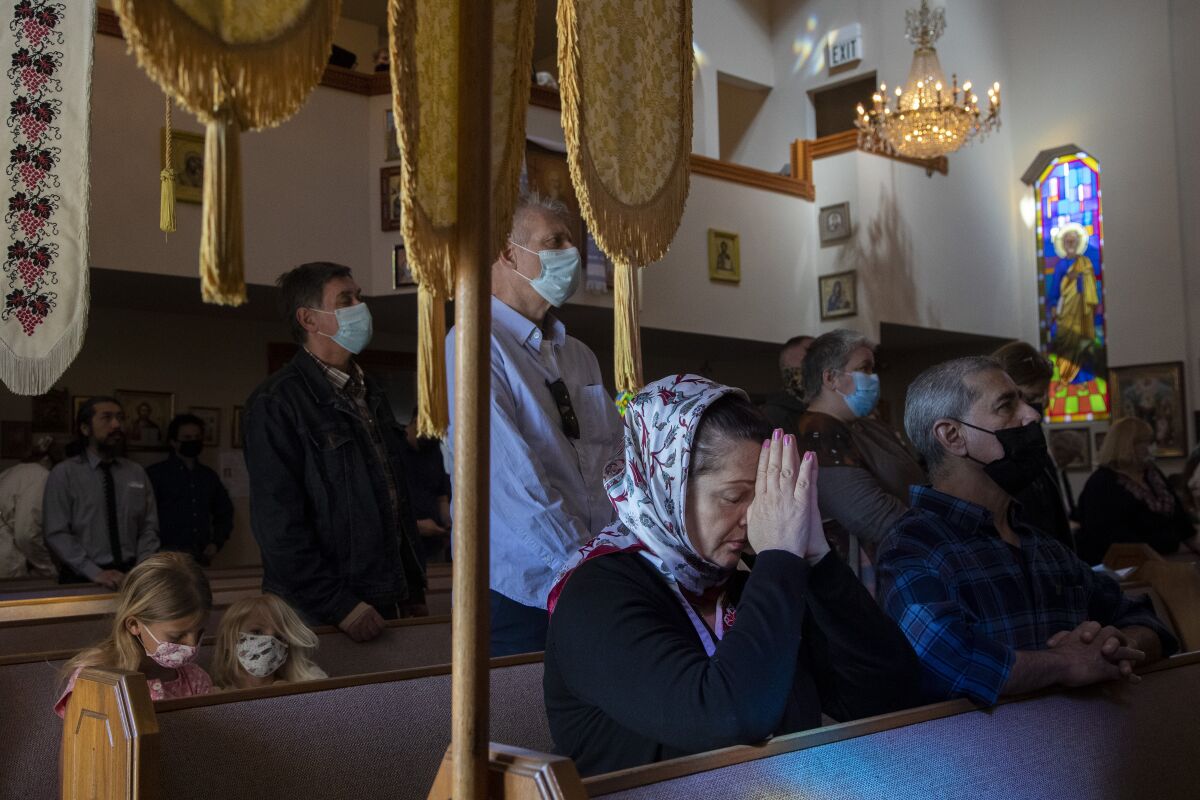 People kneel and stand in prayer inside of a church