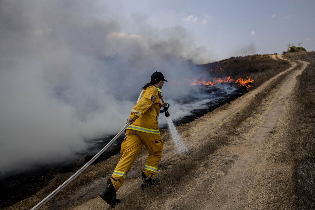 An Israeli firefighter helps extinguish a fire caused by incendiary balloons launched from the Gaza Strip on Wednesday.