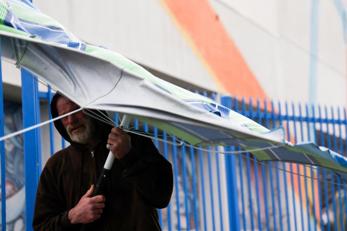 A man holds a patio umbrella during a rainy day