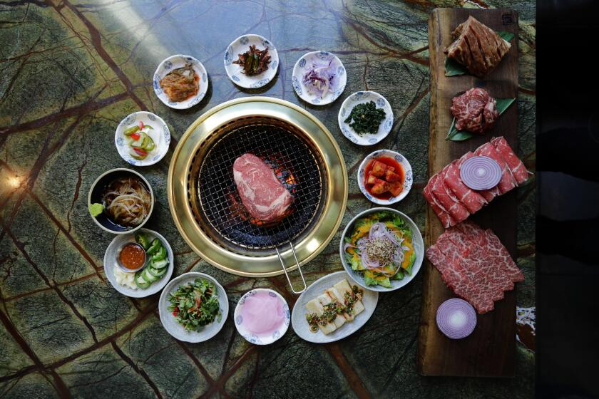 Myung J. Chun  Los Angeles Times A rib-eye, center, on the grill at Jeong Yuk Jeom in Koreatown, surrounded by assorted banchan including a few types of kimchi.