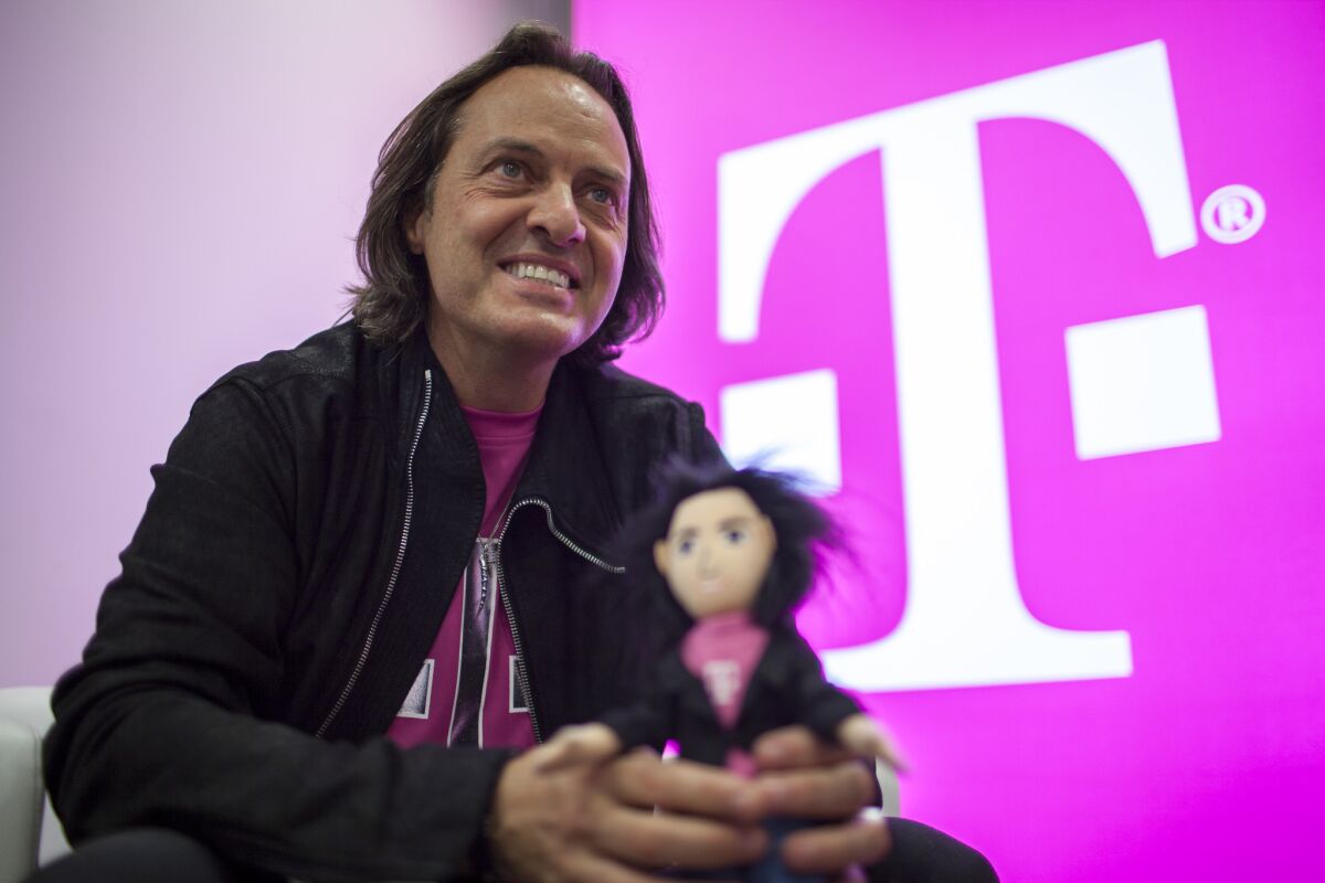 T-Mobile CEO John Legere holds a doll of himself during a media event in 2014.