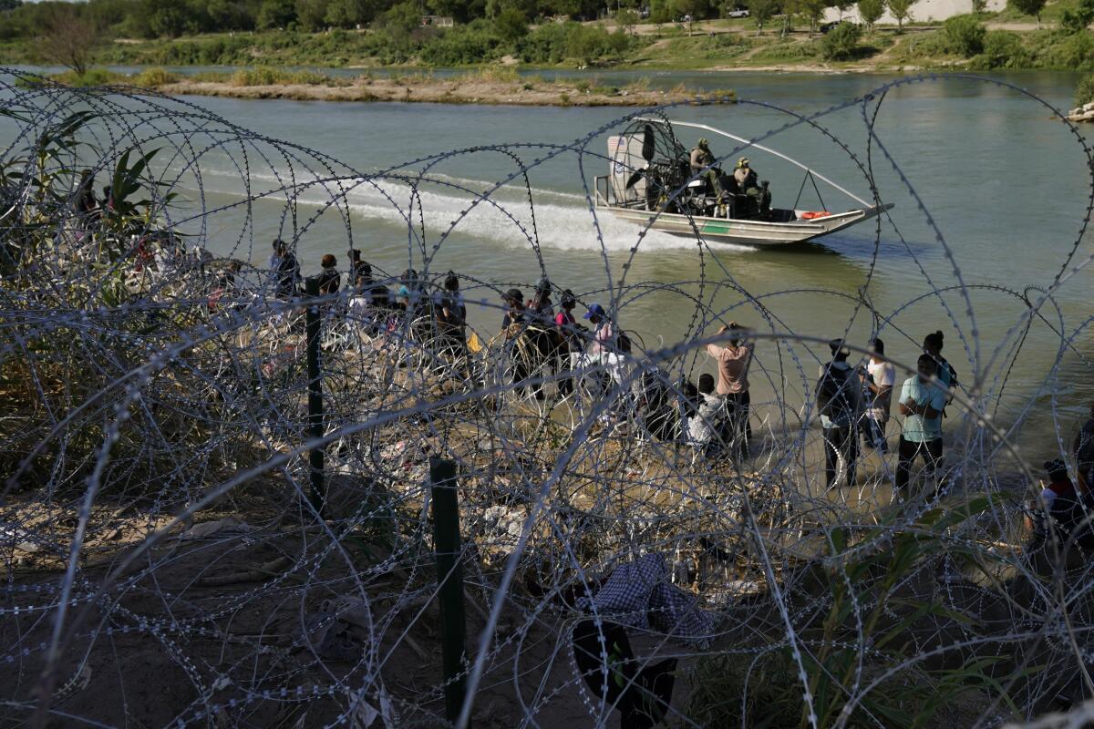 Migrants who crossed into the U.S. from Mexico are met with concertina wire along the Rio Grande.