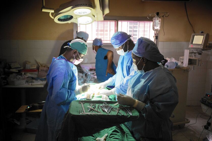 Dr. Martin Salia, left, performs surgery near Freetown, Sierra Leone, in April. Salia later contracted Ebola and died during treatment in the United States.