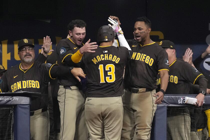 San Diego Padres' Manny Machado is congratulated by teammates in the dugout after hitting a three-run home run during the ninth inning of a baseball game against the Los Angeles Dodgers at the Gocheok Sky Dome Thursday, March 21, 2024, in Seoul, South Korea. (AP Photo/Lee Jin-man)