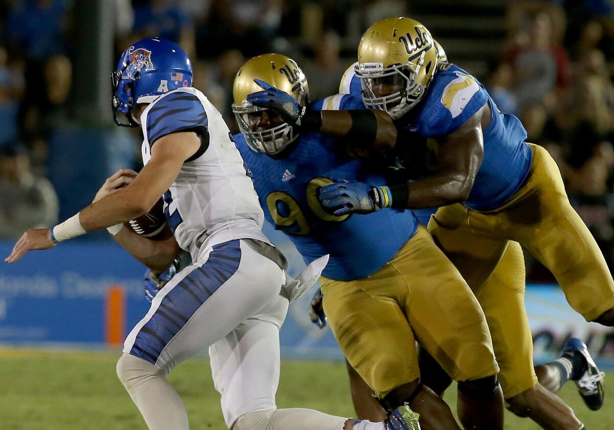 UCLA defensive linemen Wllis McCarthy (90) and Owamaagbe Odighizuwa close in on a sack of Memphis quarterback Paxton Lynch in the fourth quarter Saturday at the Rose Bowl.