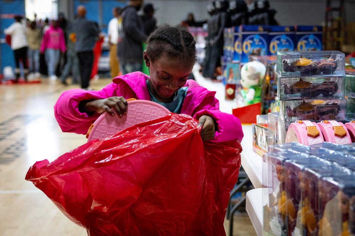 A little girl is excited to put a new toy in her bag at Top Dawg Entertainment's  annual event at the Nickerson Gardens housing project Wednesday in Los Angeles.