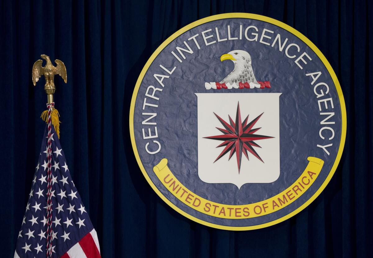 The CIA seal hangs on a wall next to an American flag