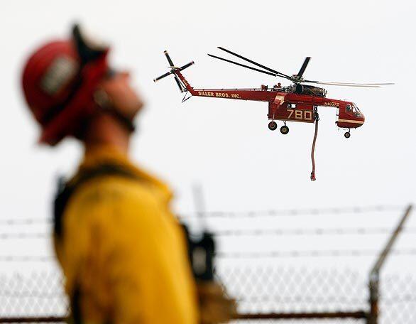 A water-dropping helicopter hovers near the southwestern flank of the Station fire, where California Office of Emergency Services firefighters monitor the progress.
