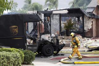 SANTEE, CA - OCTOBER 11: A firefighter walks by the debris of a fatal plane crash on Monday, Oct. 11, 2021 in Santee, CA. A small plane crashed into a UPS truck and then struck two homes, which were destroyed by fire at the intersection of Jeremy Street and Greencastle Street in Santee. (K.C. Alfred / The San Diego Union-Tribune)