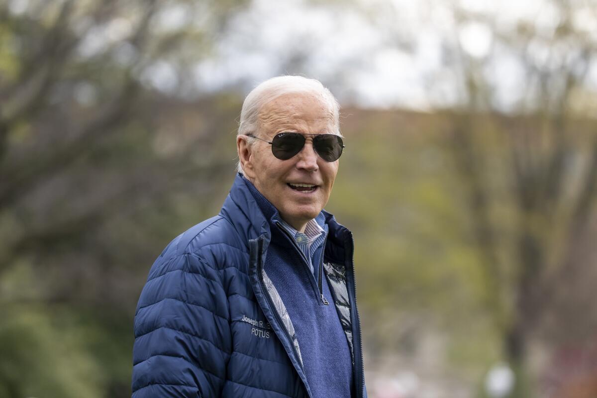 President Biden walks outdoors in sunglasses