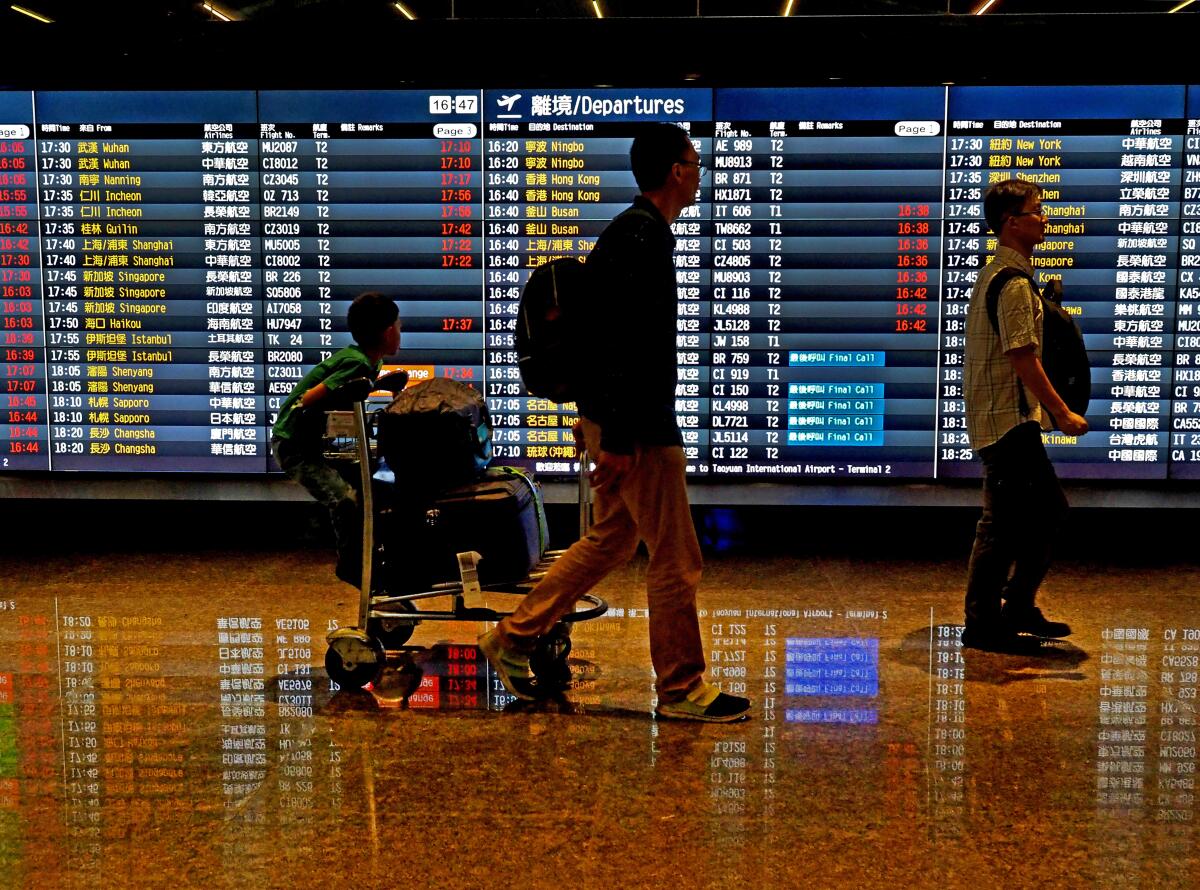 Passengers walk past a flight information board at the Taoyuan International Airport in Taoyuan County, northern Taiwan, on May 24, 2018.