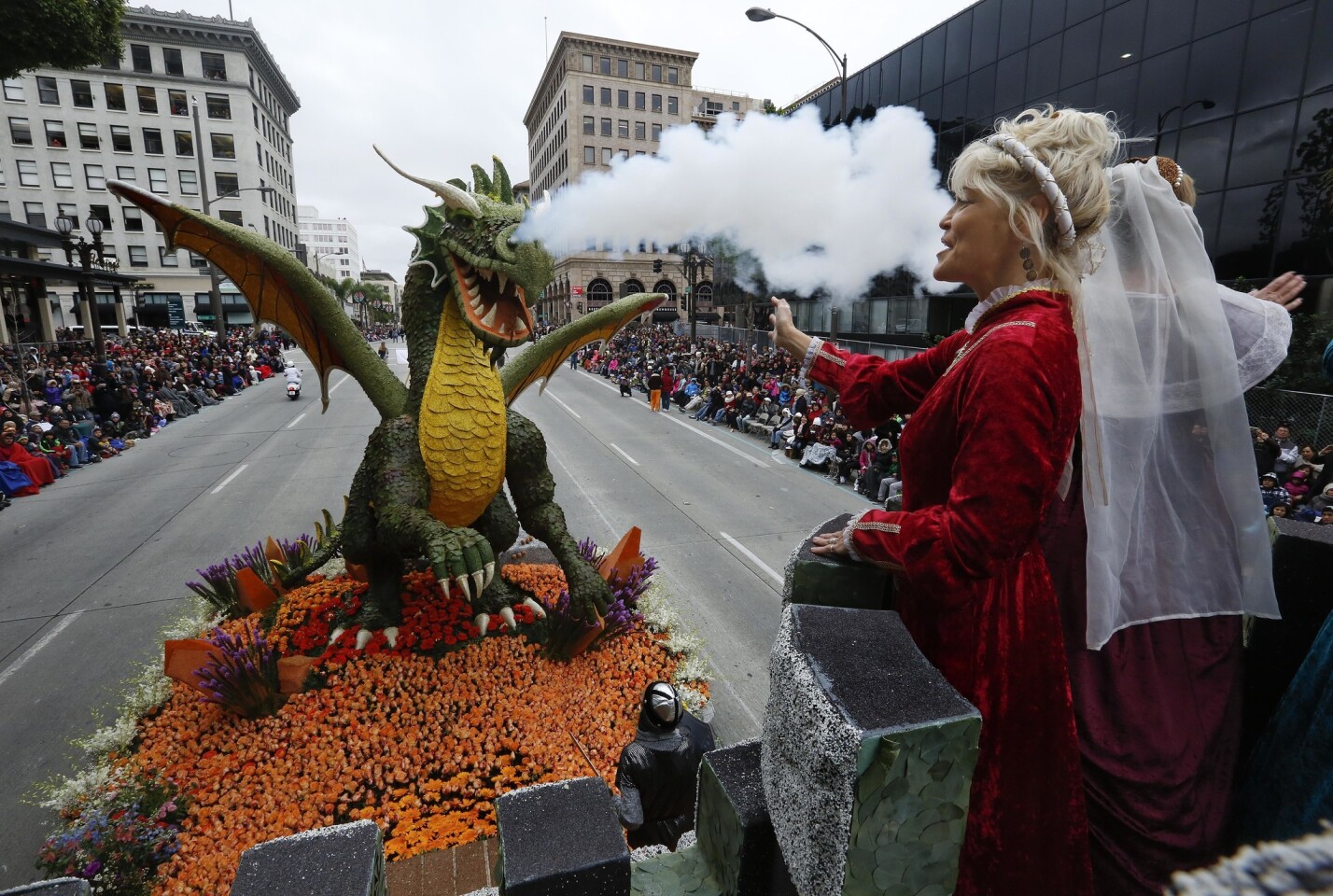 Beth Campbell, left, dressed as a medieval princess, wave to the crowd as the Rose Parade float from the City of Torrance makes its way along Colorado Blvd. in Pasadena on Monday.