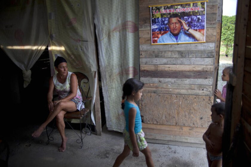 Yadaira Nunez, 43, sits in her wooden shack next to a poster of Venezuela's late president, Hugo Chavez, at a squatter settlement near Tacarigua, Venezuela.