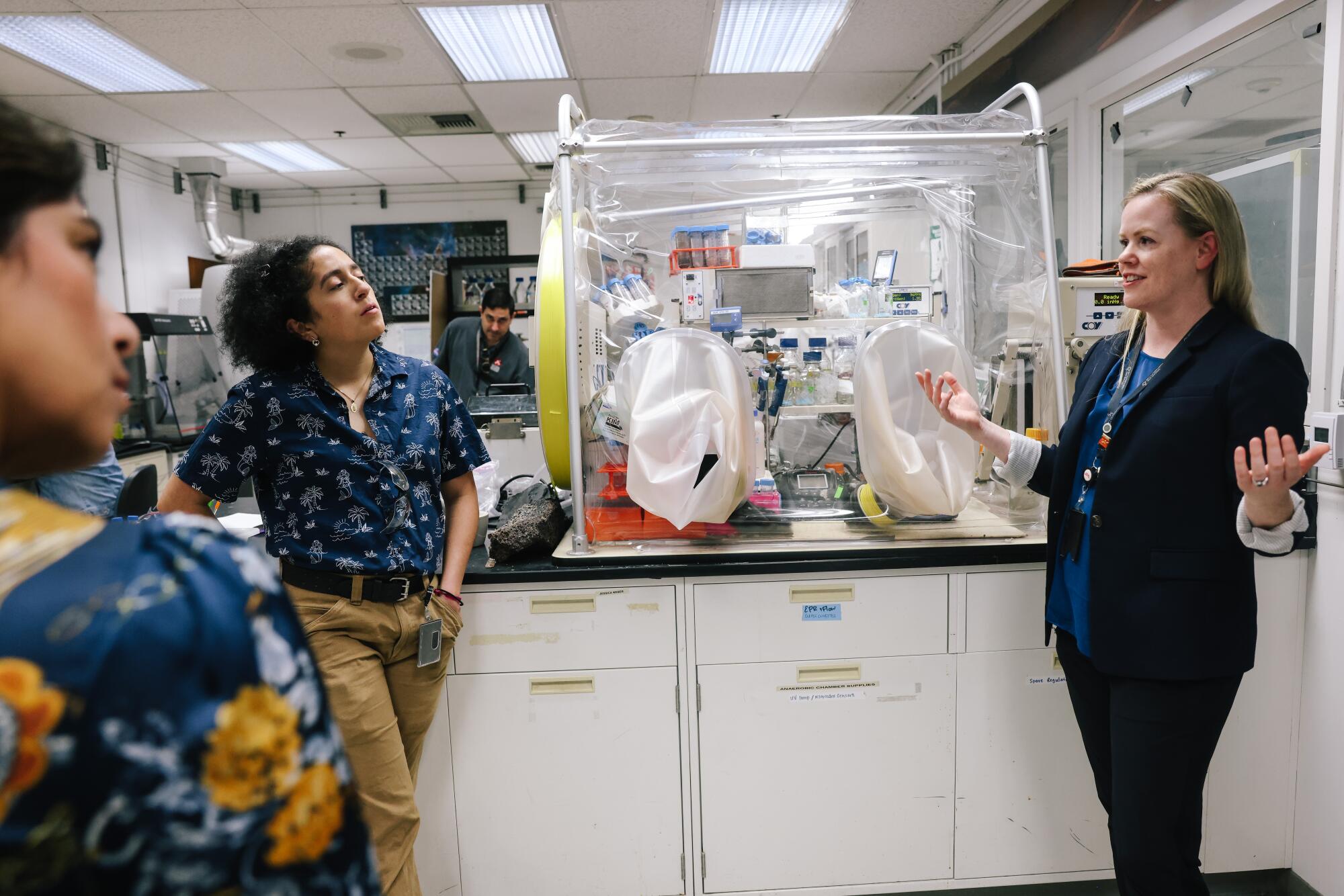 Laurie Barge, a JPL scientist, gestures while speaking to students in a lab setting. 