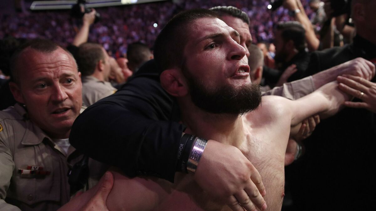 Khabib Nurmagomedov is held back outside the cage after fighting Conor McGregor in a lightweight title mixed martial arts bout at UFC 229.