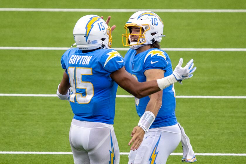 INGLEWOOD, CA - OCTOBER 25: Chargers quarterback Justin Herbert, right, celebrates with wide receiver Jalen Guyton after he caught Herbert's 70-yard touchdown pass in the third quarter against the Jaguars at an empty SoFi Stadium on Sunday, Oct. 25, 2020 in Inglewood, CA. The rookie quarterback finished 27 of 43 for 347 yards and three touchdowns. He also led the Chargers in rushing with 66 yards on nine carries and scored a touchdown on the ground. Herbert's 66 yards set a franchise record for rushing yards by a quarterback. (Allen J. Schaben / Los Angeles Times)