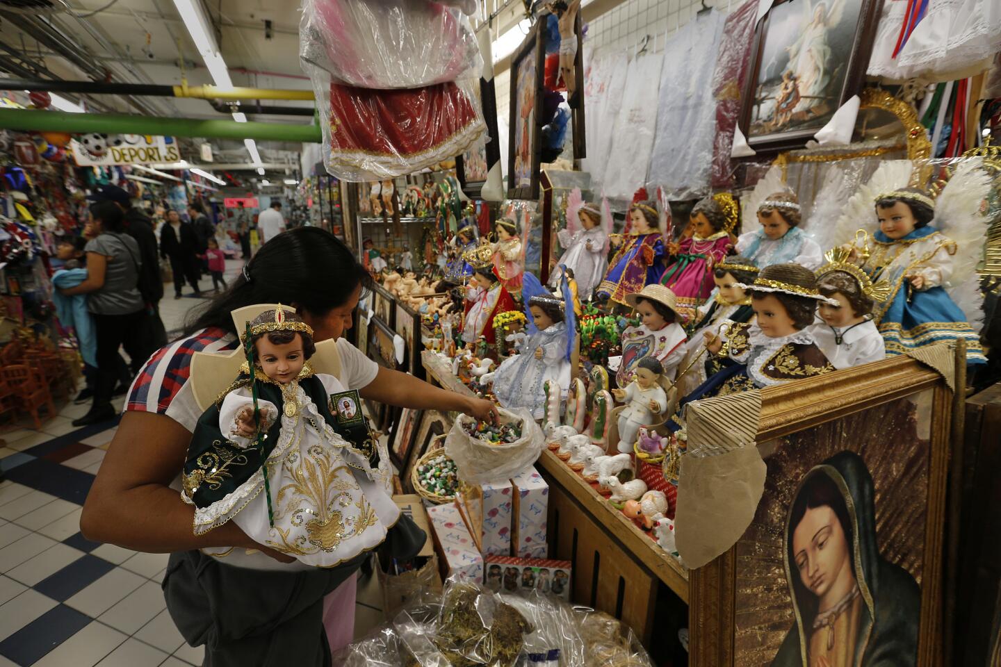 Rosario Gonzalez holds her baby Jesus doll that was repaired and dressed as Saint Judas Thaddaeus, the patron saint of hope, at Que Linda General Store in Boyle Heights for infant Christ's first church visit on Candlemas, Feb. 2.