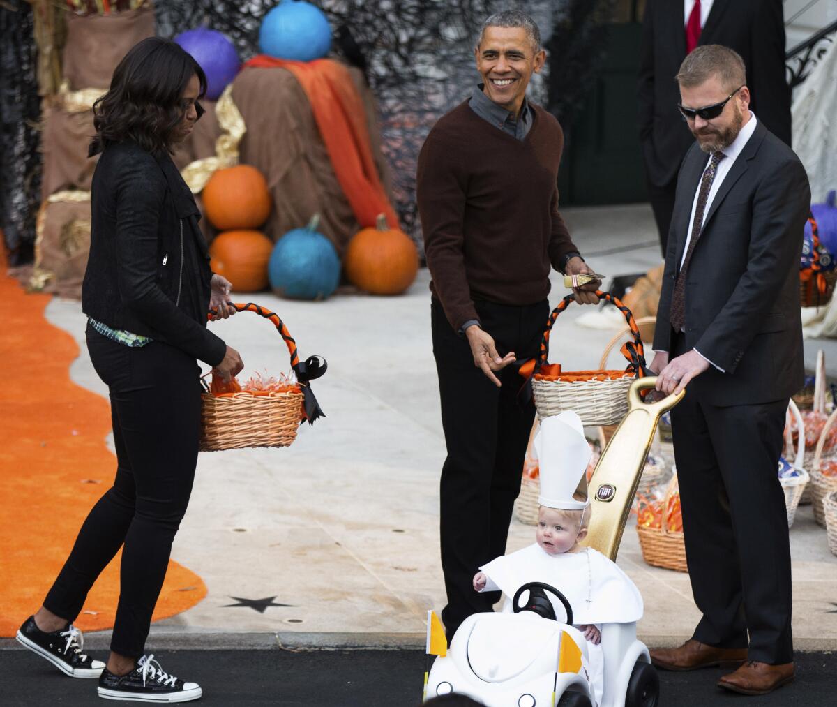 El presidente Barack Obama y la primera dama Michelle Obama, a la izquierda, saludan a un niño vestido de pontífice en su papamóvil durante la fiesta de Halloween que se efectuó en el Jardín Sur de la Casa Blanca en Washington, el viernes 30 de octubre de 2015. A la celebración asistieron niños locales y de familias del ejército. (AP Foto/Andrew Harnik)