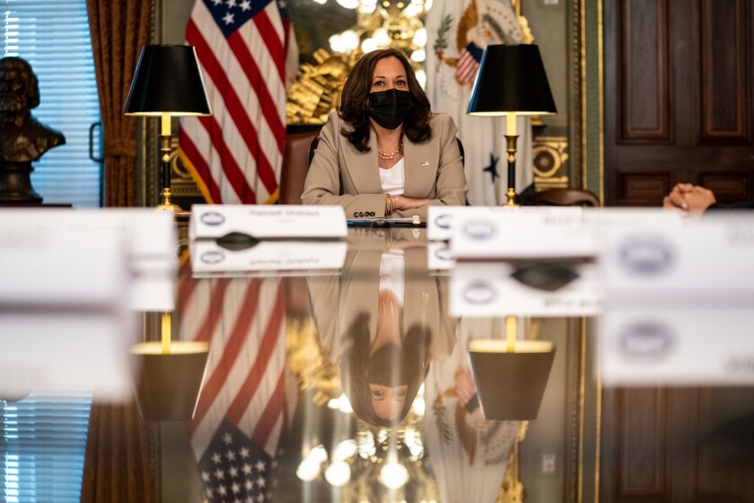 Vice President Kamala Harris sits at a large table 