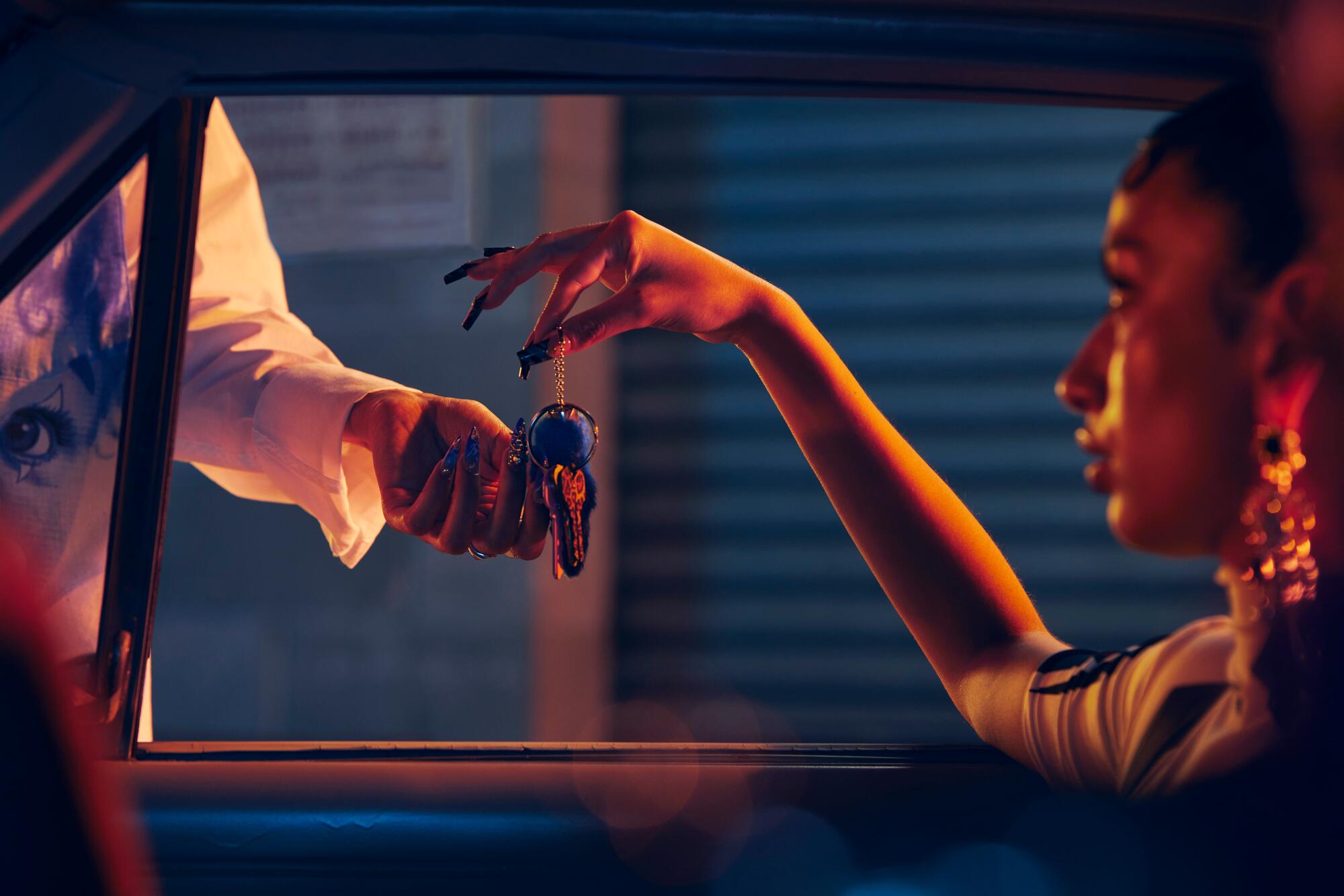 A person hands off keys to a valet with an outstretched hand.