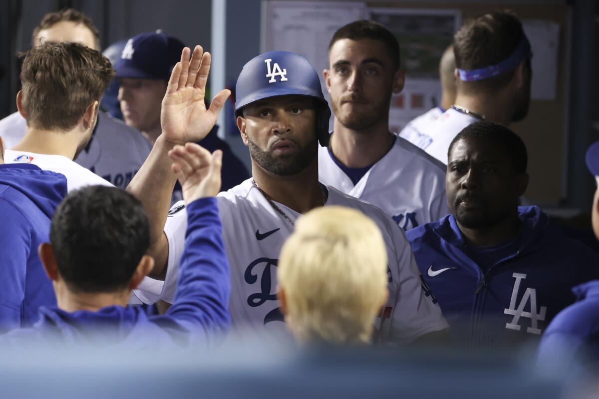 Dodgers' Albert Pujols celebrates with teammates in the dugout.