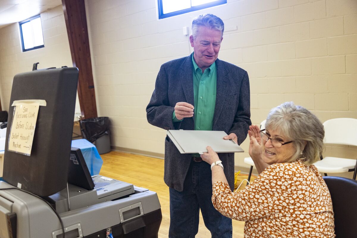 Idaho Gov. Brad Little laughs as he takes an "I Voted" sticker from poll worker Carla Stark after casting his ballot in Idaho's Primary Election in Emmett, Idaho, Tuesday, May 17, 2022. (AP Photo/Kyle Green)