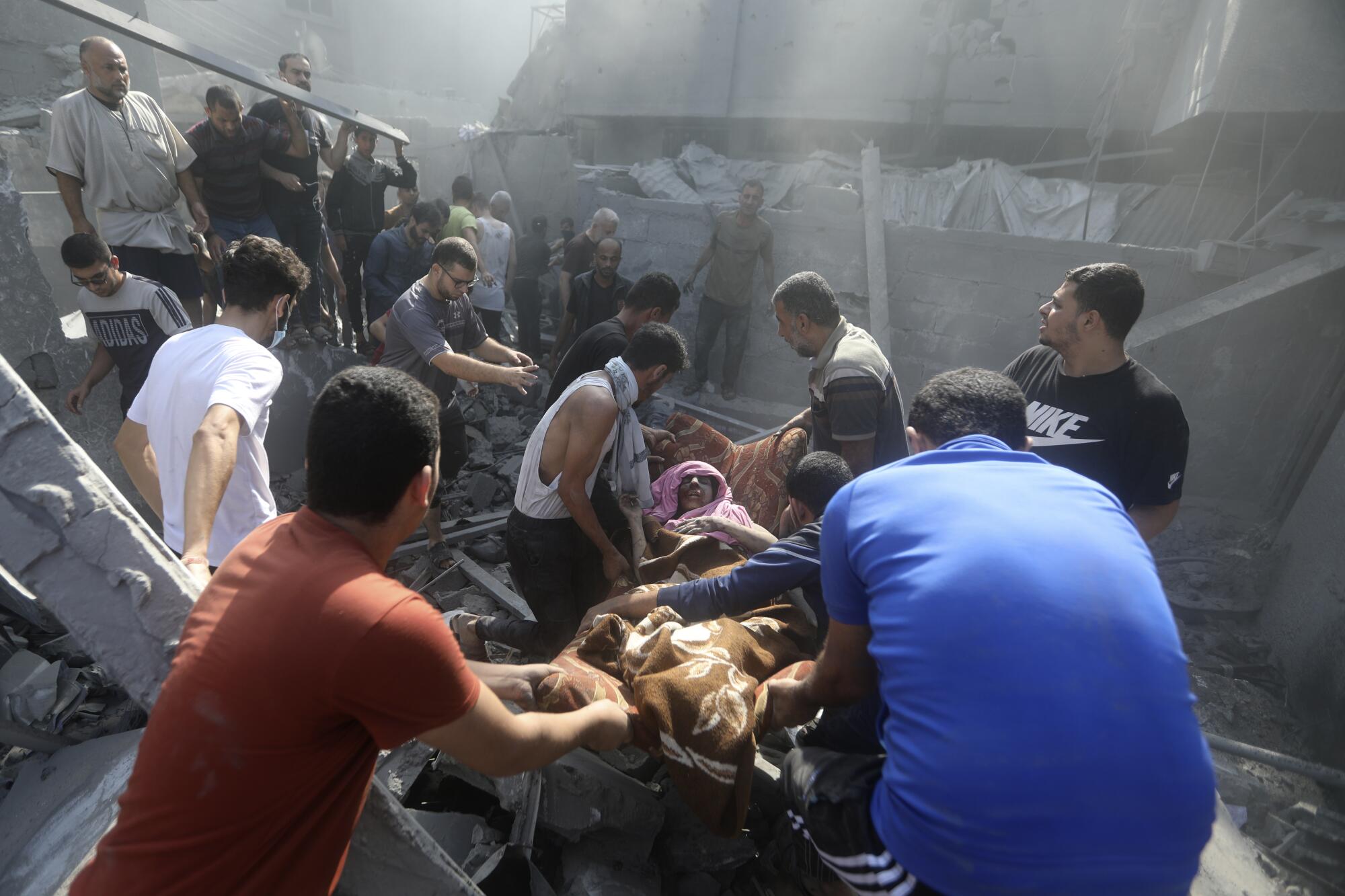 People carry an injured woman recovered from rubble of destroyed building in Gaza