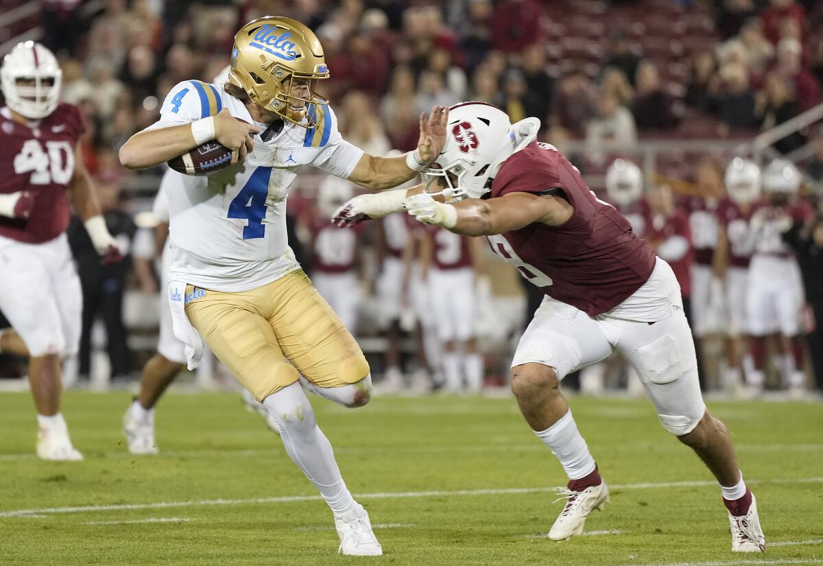 UCLA quarterback Ethan Garbers tries to fend off Stanford linebacker Tristan Sinclair.