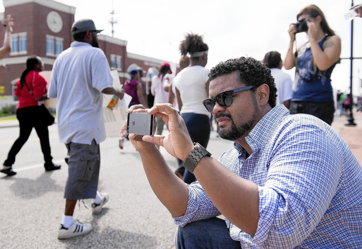 St. Louis Alderman Antonio French photographs protesters marching through downtown Ferguson, Mo.