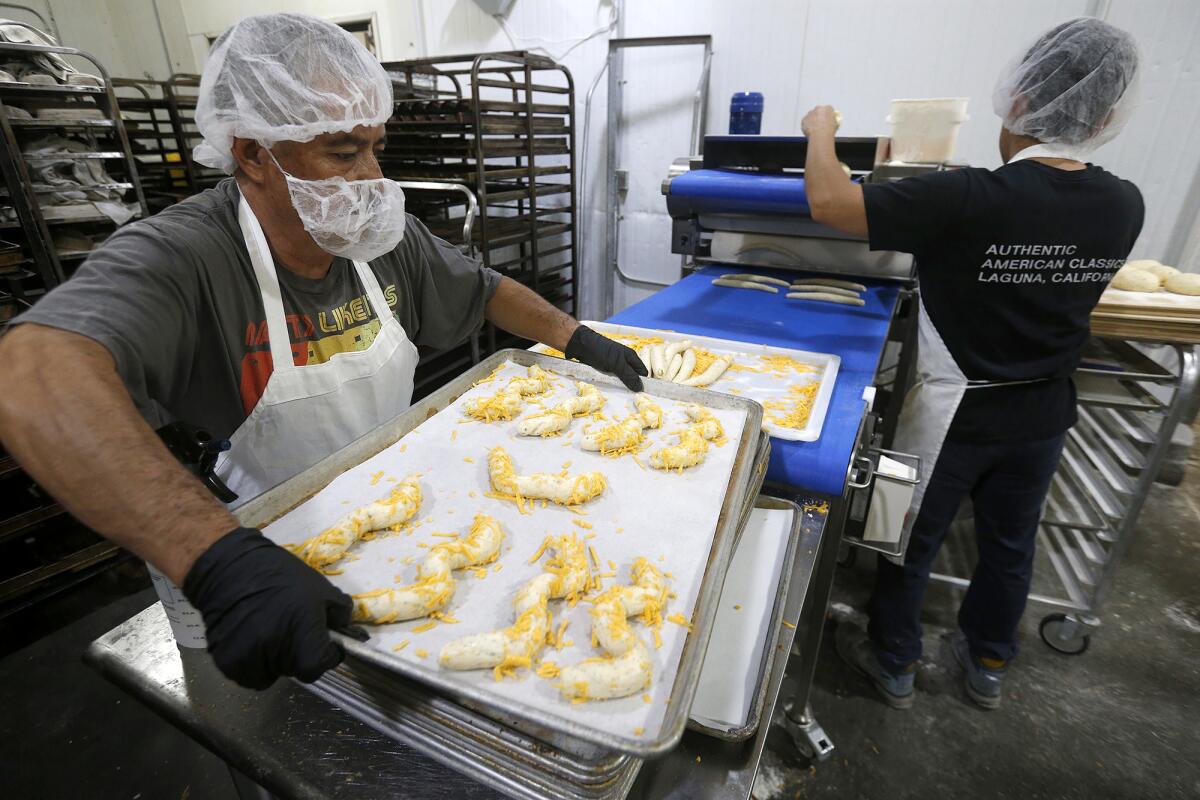 Two bakers roll custom dough designs prior to baking at the Bread Artisan Bakery in Santa Ana.