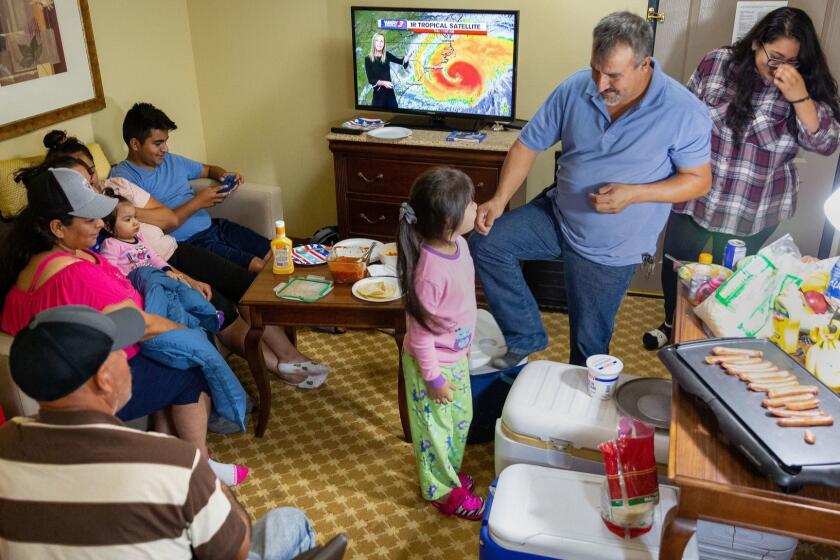The Ramos family prepares dinner and watches the weather forecast in their hotel room at the Country Inn and Suites Thursday night in Wilmington, N.C. where they waited out Hurricane Florence.
