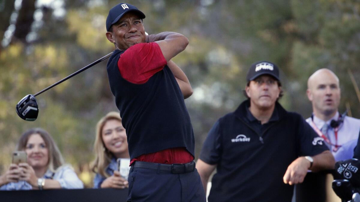 Tiger Woods hits off the 16th tee as Phil Mickelson watches during a golf match at Shadow Creek golf course, Friday, Nov. 23, 2018, in Las Vegas. (AP Photo/John Locher)