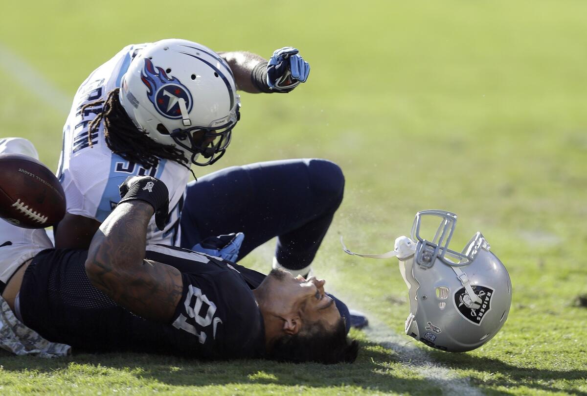 Oakland Raiders tight end Mychal Rivera, bottom, loses his helmet after being hit by Tennessee Titans free safety Michael Griffin during a game in November. Rivera suffered a concussion on the play.