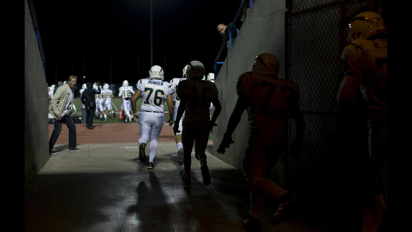 Edison players enter the field at Veterans Stadium through a tunnel before their Sunset League game against Los Alamitos on Thursday night in Long Beach.