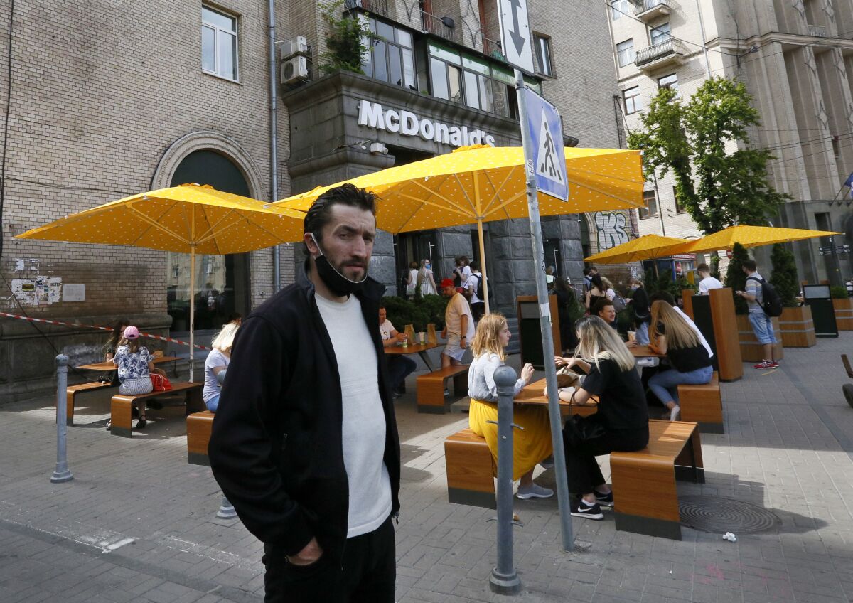 Gente come en las mesas en la acera de un McDonald's en el centro de Kiev, Ucrania, 