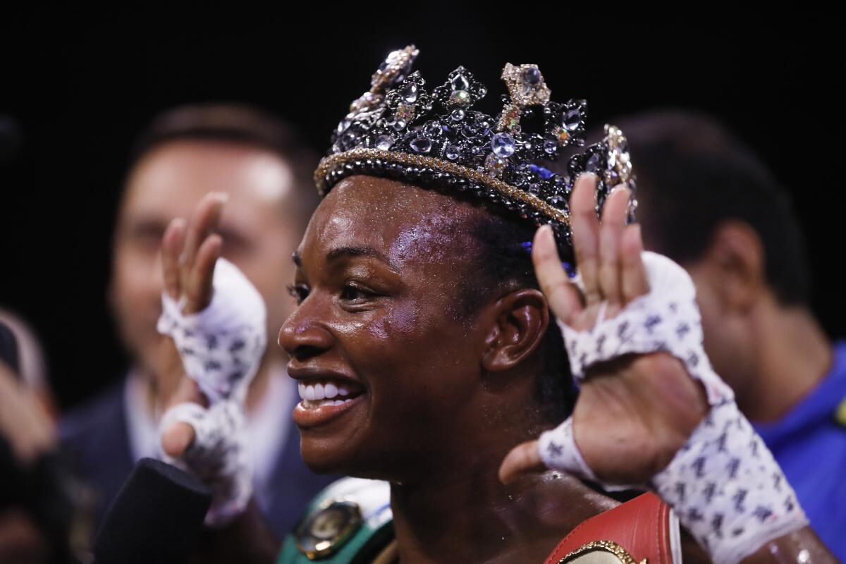 Claressa Shields smiles and wears a crown while showing her wrapped hands.
