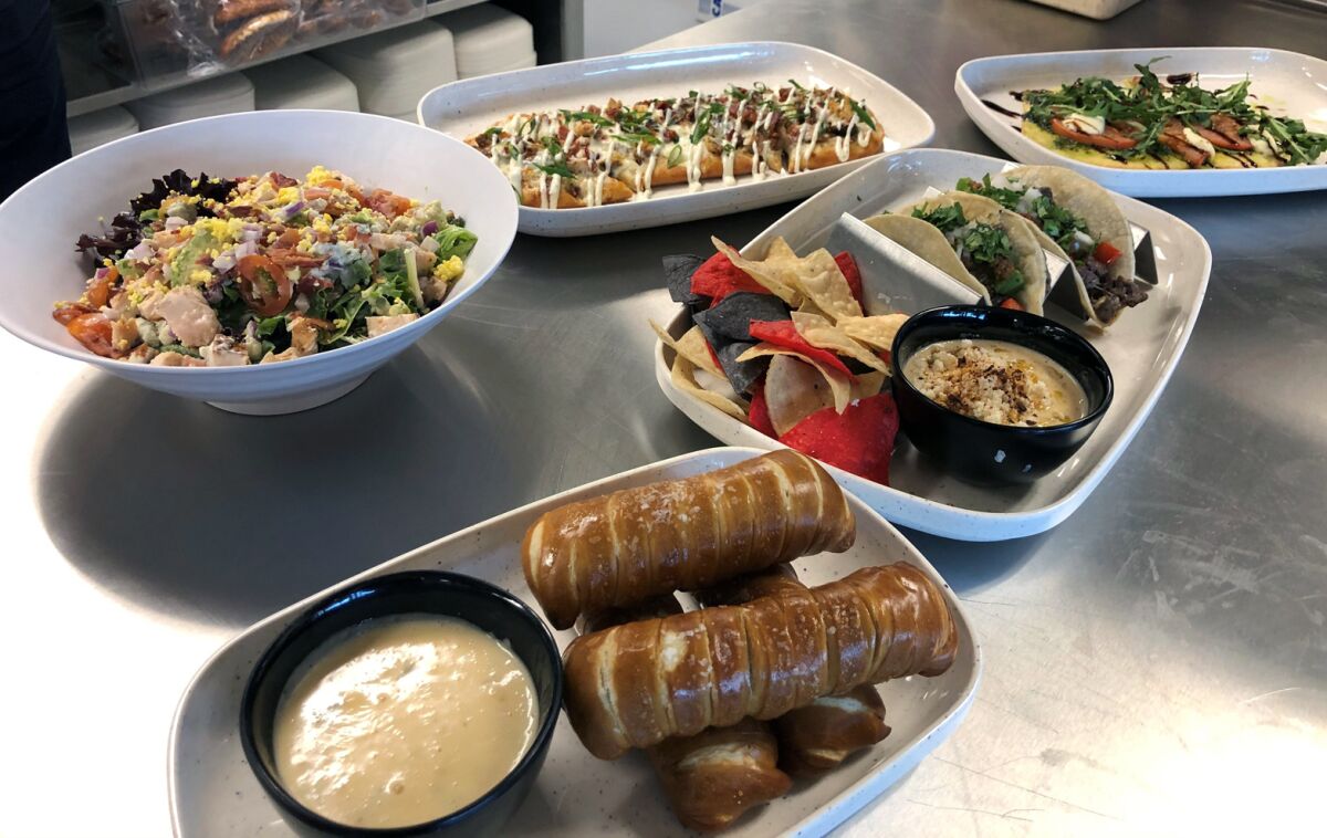 Some of the new made-from-scratch food items that will be served at the Cinépolis Luxury Cinemas La Costa Town Square opening in Carlsbad on Feb. 7. Clockwise from top left: Cobb salad, chicken bacon ranch pizza, Caprese pizza, Asada steak tacos with roasted corn and tortilla chips and Bavarian-style pretzel stix with queso blanco dip.