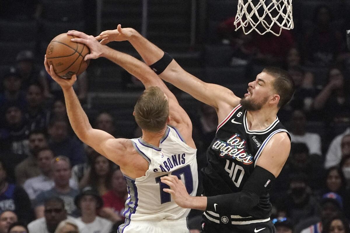 Clippers center Ivica Zubac reaches above Kings center Domantas Sabonis while trying to block his layup.
