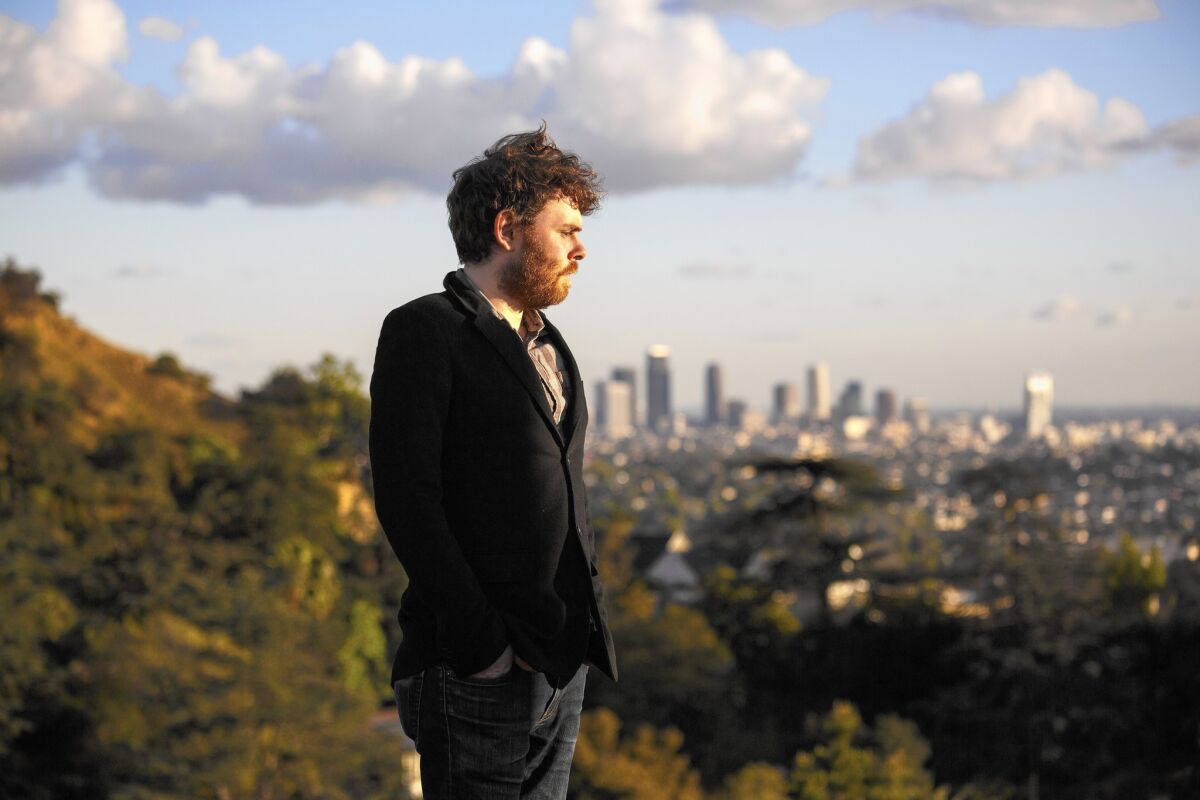 Musician Gabriel Kahane, standing in Los Feliz, with downtown Los Angeles beyond.