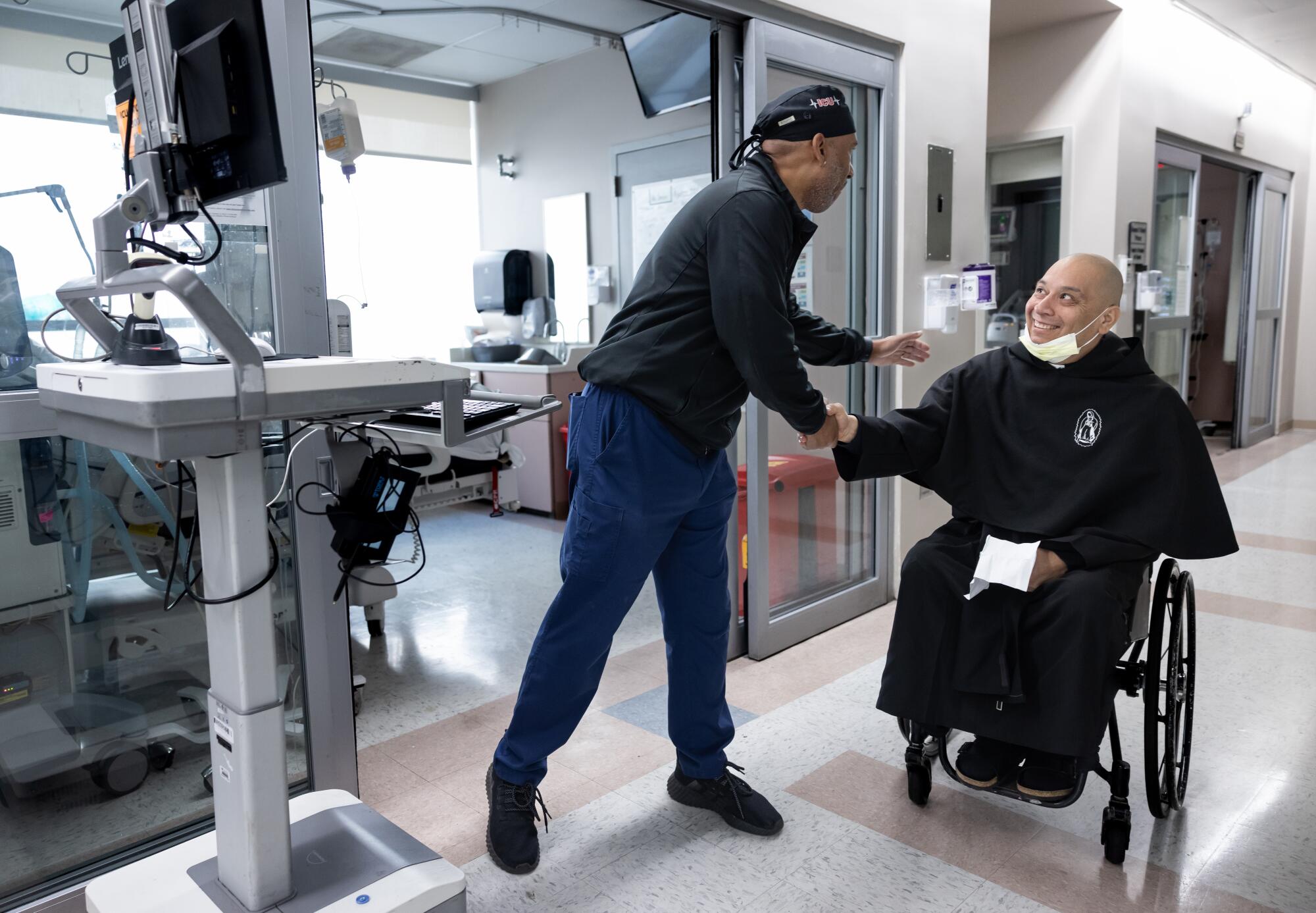 Father Cesar Galan says hello to ICU nurse Stacy Douglas while making his rounds.