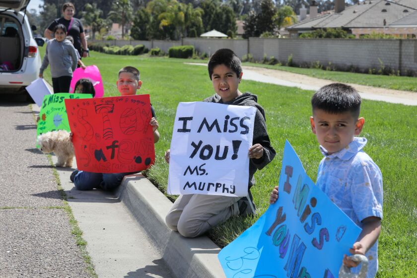 March 27, 2020_Escondido, California, USA_| Reidy Creek Elementary School students wait along Conway Drive, near North Avenue for the caravan of their teachers from nearby Reidy Creek Elementary School to drive by and greet them, middle is third grader David Duran. His teacher that he misses is Ms. Dale Murphy. |_Photo Credit: Photo by Charlie Neuman