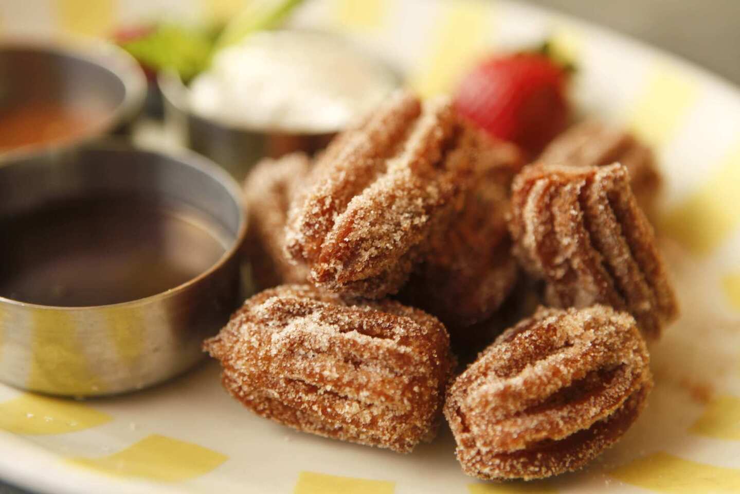 The churro tots are dulce de leche-infused churros covered with cinnamon sugar, served with chocolate and caramel dipping sauces and ample whipped cream.