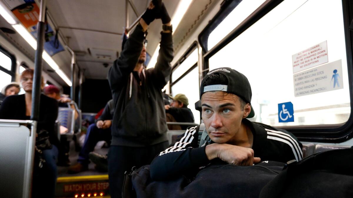 Nicholas Trullench, right, rides with others on an Orange County Transportation Authority bus from a homeless encampment along the Santa Ana River in Anaheim to a nearby motel last month after the county began clearing the camp.