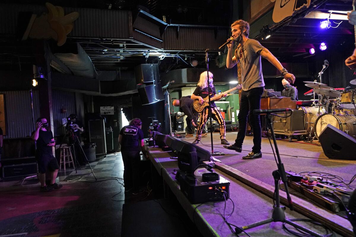 FILE - In this Oct. 26, 2020 file photo, David Shaw, foreground, frontman for the band The Revivalists, performs with actor Harry Shearer, co-author and character in the movie "This Is Spinal Tap," as they record a video stream concert with the band Galactic, inside an empty Tipitina's music club, in New Orleans. Entertainment venues in New Orleans have been given permission to start hosting live music again starting this weekend, but under strict regulations. Mayor LaToya Cantrell and city health director Jennifer Avegno announced the change Wednesday, March 10, 2021. (AP Photo/Gerald Herbert, File)