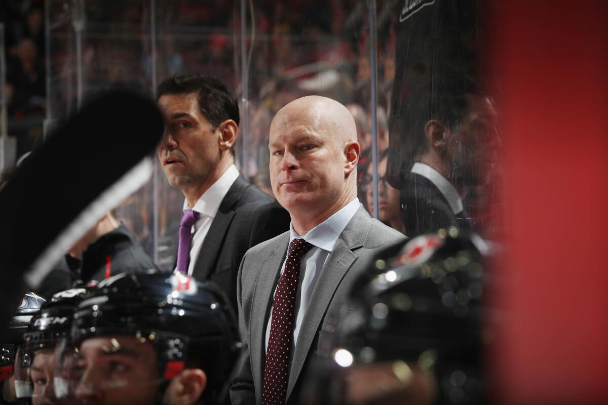Devils coach John Hynes stands behind the bench during a game against the Penguins on Feb. 19.