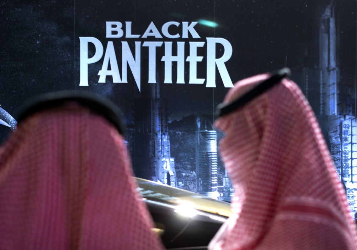 FILE - Visitors wait in front of a "Black Panther" movie banner, during an invitation-only screening, at the King Abdullah Financial District Theater, in Riyadh, Saudi Arabia, on April 18, 2018. AMC Entertainment Holdings, the world's biggest cinema chain, has decided to exit Saudi Arabia's fast-growing market in the face of intense competition. The decision, announced Monday, Jan. 30, 2023, comes less than five years after AMC opened the kingdom's first movie theater following a decades-long ban. (AP Photo/Amr Nabil, File)