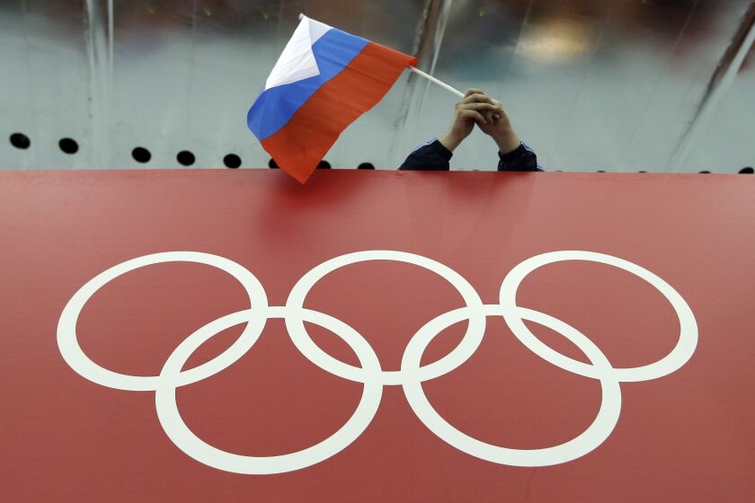 FILE - A Russian flag is held above the Olympic Rings at Adler Arena Skating Center during the Winter Olympics in Sochi, Russia on Feb. 18, 2014. Russia and its ally Belarus have been invited to compete at the Asian Games in the next step to qualify athletes for next year’s Paris Olympics. The arrangement has been brokered by the International Olympic Committee. The IOC indicated on Wednesday that it favours allowing Russians to compete at the 2024 Olympics as neutral athletes. (AP Photo/David J. Phillip, File)